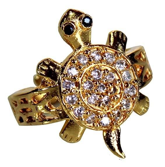 Gold turtle-shaped ring with gemstones on a white background
